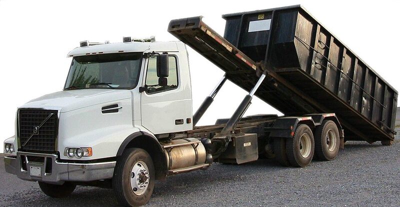 White Volvo roll-off truck tipping a large black maxi skip bin
