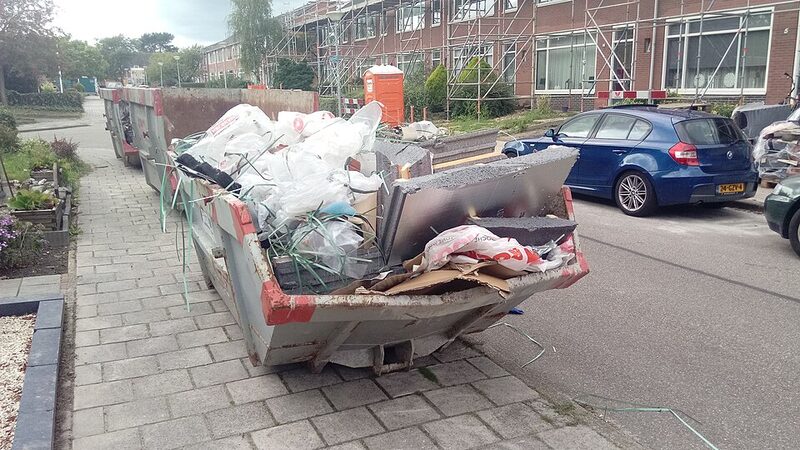 Open 2 cubic metre mini skip bin full of renovation waste on a residential street